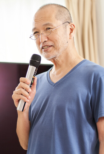 ワイヤレスマイクで案内する職員の男性
